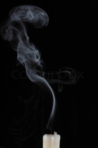 Smoke and extinguished the candle wax on a black background